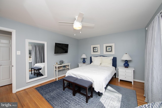 bedroom with a ceiling fan, baseboards, and wood finished floors