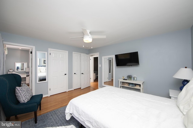 bedroom featuring multiple closets, ceiling fan, baseboards, and wood finished floors