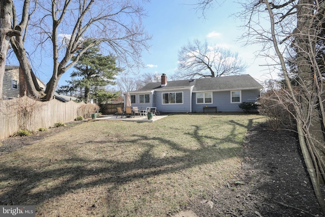 rear view of house featuring a yard, a fenced backyard, a chimney, and a patio