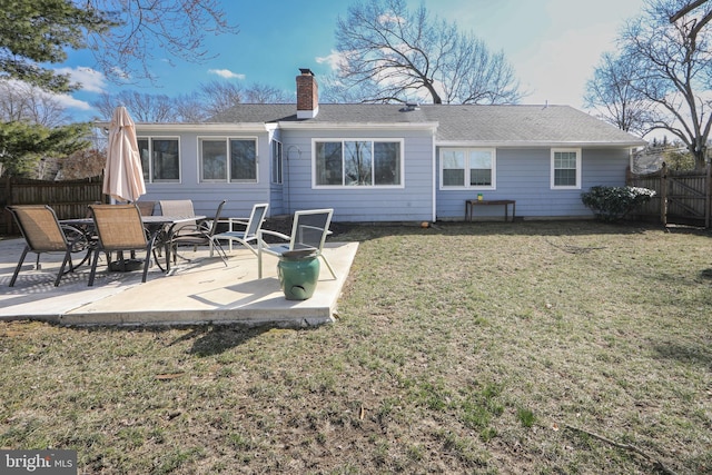 rear view of property featuring a patio, a lawn, a chimney, and fence