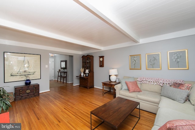 living room with baseboards, beam ceiling, and light wood-style floors