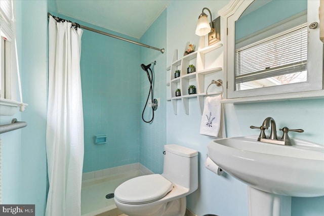 bathroom with a sink, a shower stall, and toilet