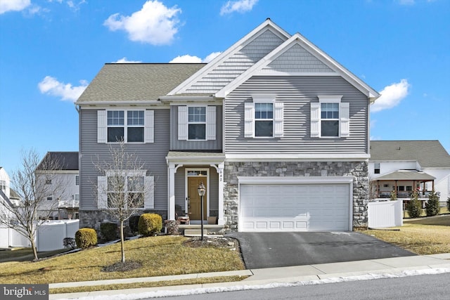 view of front of home with stone siding, driveway, an attached garage, and central AC unit