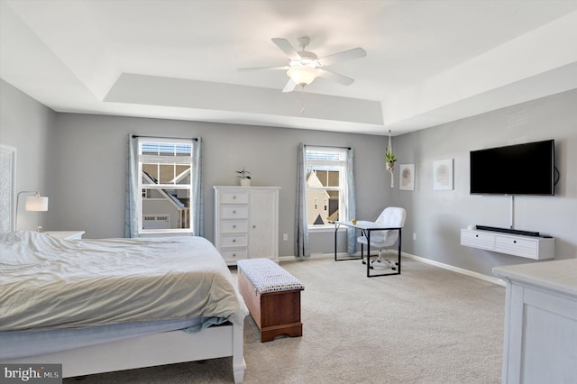 bedroom featuring ceiling fan, baseboards, a raised ceiling, and light colored carpet