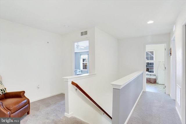 interior space with light carpet, visible vents, and an upstairs landing