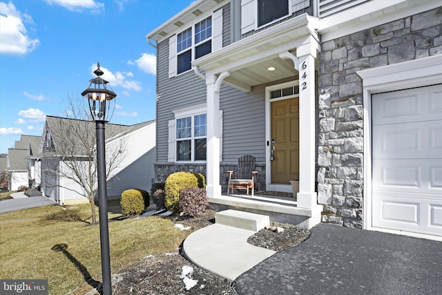 property entrance with stone siding and a lawn