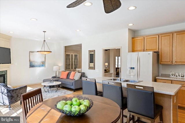 dining area featuring a ceiling fan, light wood-type flooring, recessed lighting, and a premium fireplace