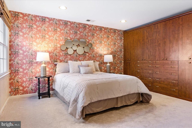 bedroom featuring light carpet, wallpapered walls, visible vents, and baseboards