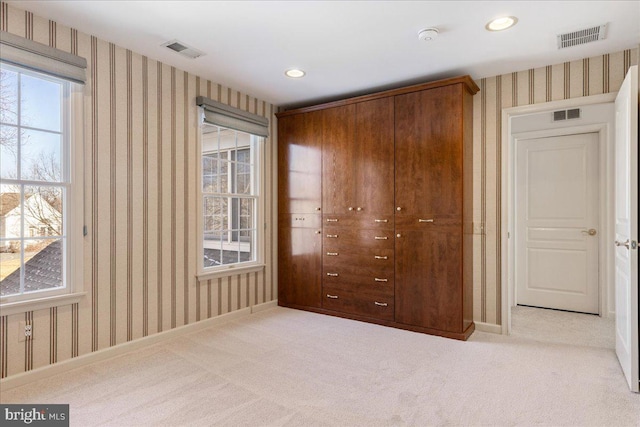 unfurnished bedroom with light colored carpet, visible vents, and wallpapered walls