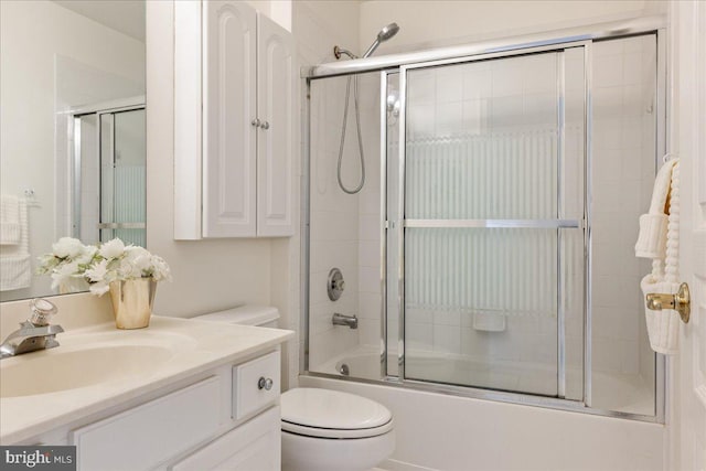 full bath featuring toilet, bath / shower combo with glass door, and vanity