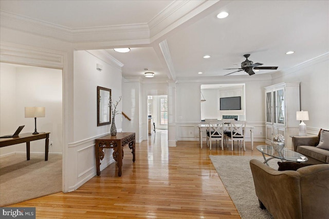 living area with ornamental molding, light wood-type flooring, a decorative wall, and decorative columns