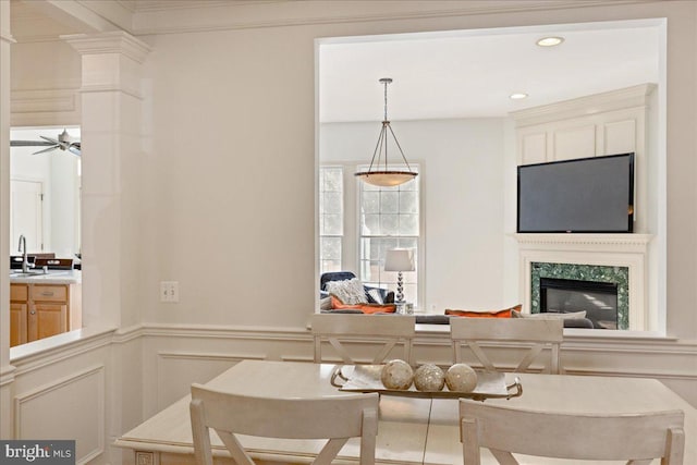 kitchen featuring a decorative wall, a sink, a high end fireplace, light countertops, and decorative light fixtures