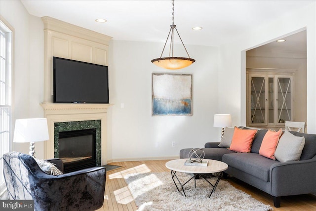 living area featuring baseboards, a fireplace, light wood-style flooring, and recessed lighting