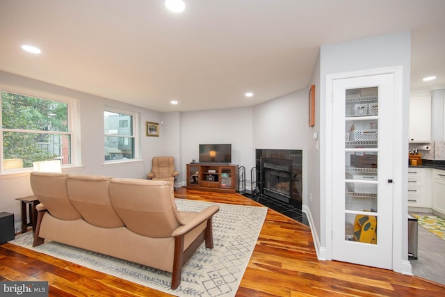 living room featuring recessed lighting, baseboards, a tile fireplace, and wood finished floors