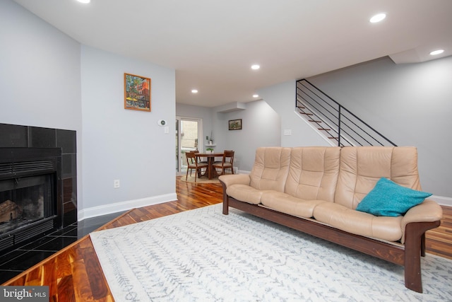 living room with baseboards, wood finished floors, stairs, a fireplace, and recessed lighting