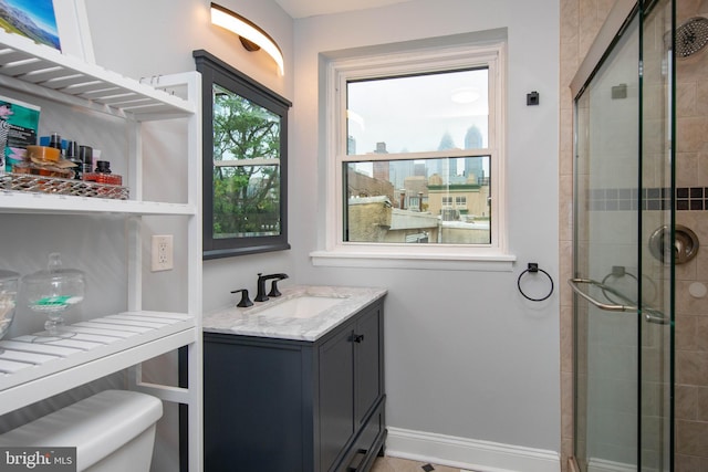 bathroom with tiled shower, vanity, and baseboards