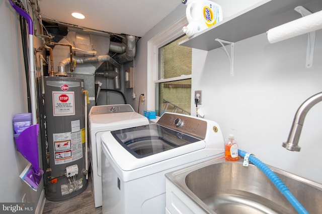 laundry area with gas water heater, washing machine and dryer, a sink, wood finished floors, and laundry area