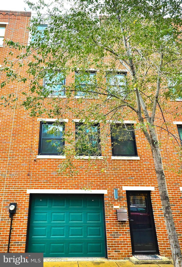 multi unit property featuring a garage and brick siding