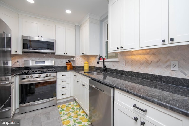 kitchen with stainless steel appliances, a sink, white cabinetry, decorative backsplash, and dark stone counters