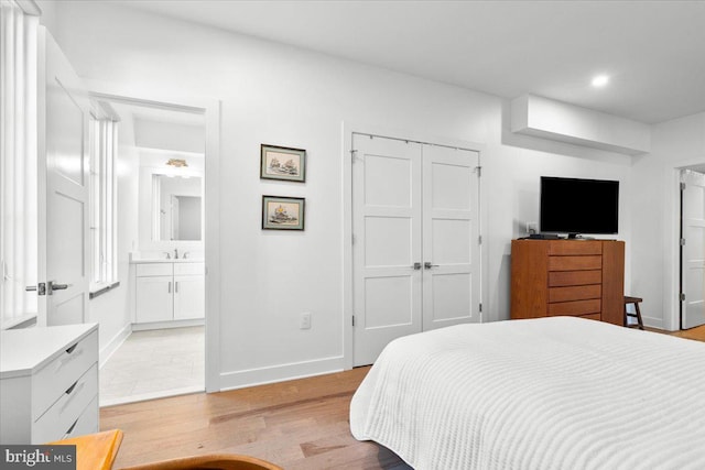 bedroom with light wood-style flooring, recessed lighting, a sink, baseboards, and a closet