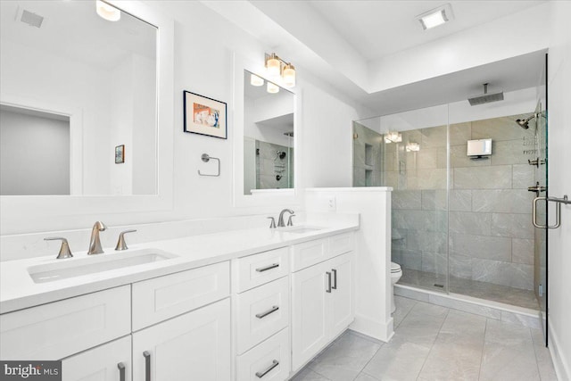 full bath with toilet, a shower stall, double vanity, and a sink