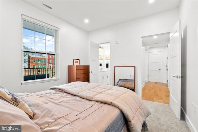 bedroom with recessed lighting, wood finished floors, visible vents, baseboards, and ensuite bath