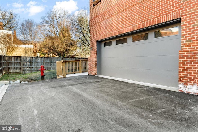 garage featuring driveway and fence