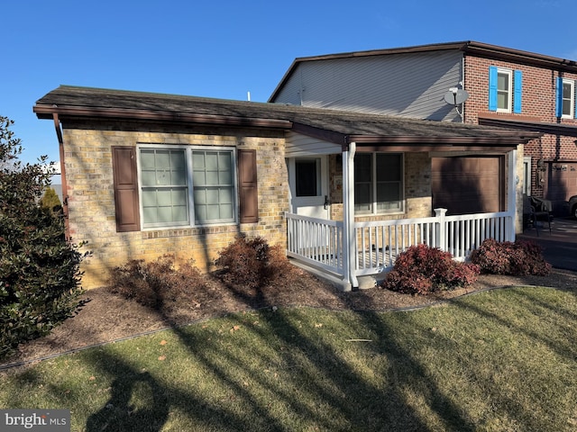 view of front of house with covered porch, brick siding, and a front yard