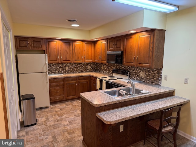 kitchen with a peninsula, white appliances, a sink, light countertops, and decorative backsplash