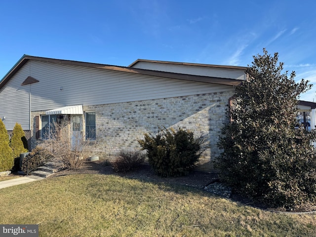 view of side of home with brick siding and a lawn