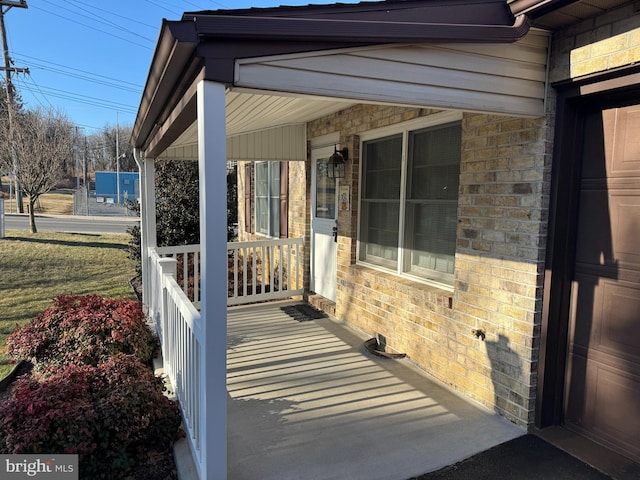 doorway to property with covered porch and brick siding