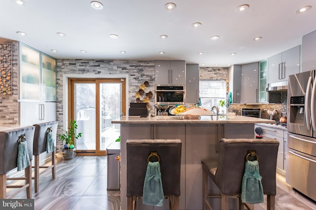 kitchen featuring appliances with stainless steel finishes, a breakfast bar area, a kitchen island, and glass insert cabinets