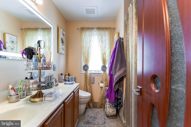 bathroom featuring double vanity, visible vents, and toilet