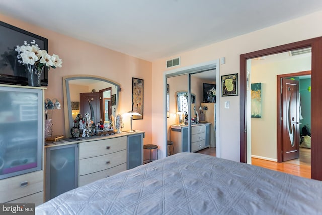 bedroom featuring light wood finished floors, visible vents, and a closet