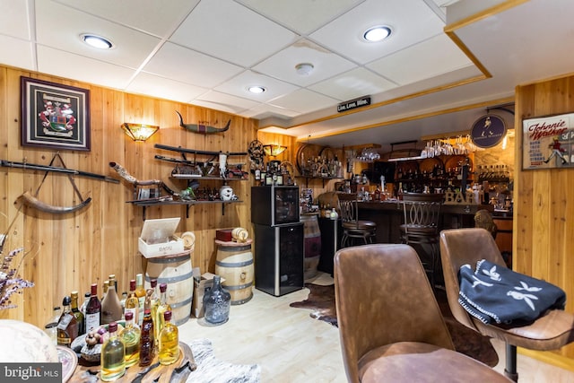 miscellaneous room with a bar, wood walls, a paneled ceiling, and wood finished floors