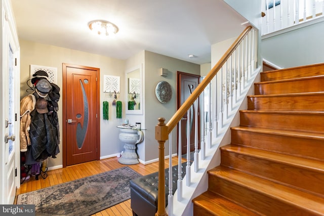 entryway with light wood-style floors, stairway, and baseboards