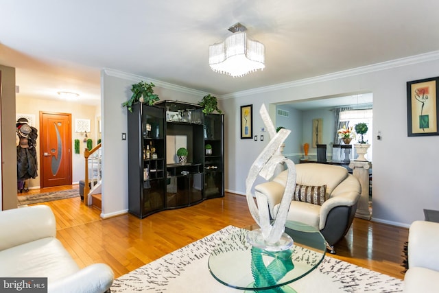 living area with crown molding, visible vents, stairway, and wood finished floors