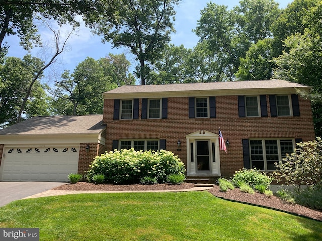 colonial house featuring brick siding, an attached garage, concrete driveway, and a front yard