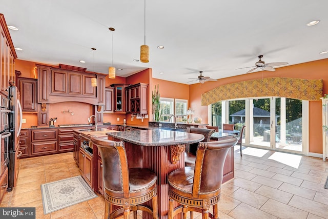 kitchen featuring a breakfast bar area, recessed lighting, dark stone counters, glass insert cabinets, and pendant lighting