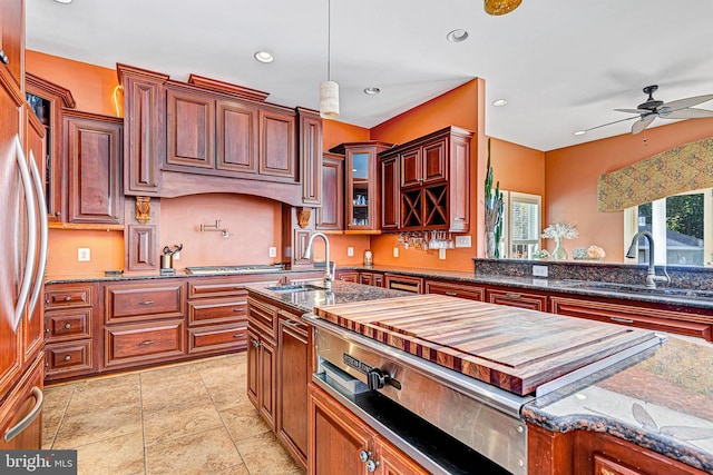 kitchen featuring dark stone countertops, a sink, glass insert cabinets, and pendant lighting