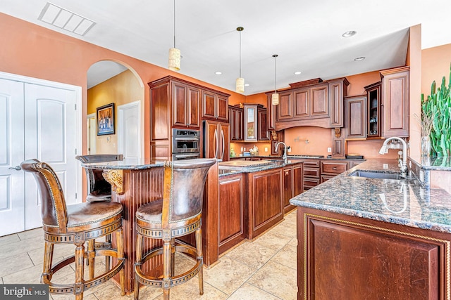 kitchen with paneled built in refrigerator, a sink, visible vents, a center island, and decorative light fixtures