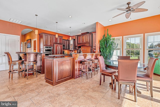 kitchen featuring a breakfast bar, visible vents, hanging light fixtures, paneled built in refrigerator, and a peninsula