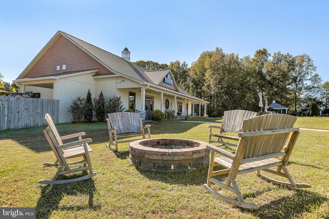 view of yard with fence, a fire pit, and a porch