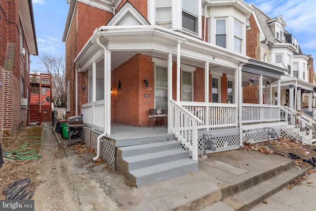 view of front of home featuring covered porch and brick siding