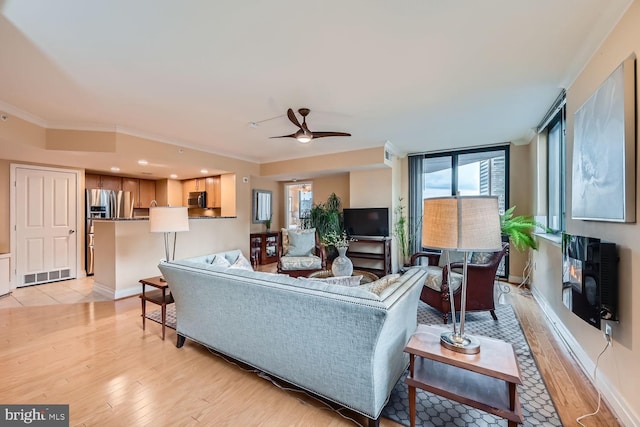 living room featuring light wood-style flooring, visible vents, and crown molding