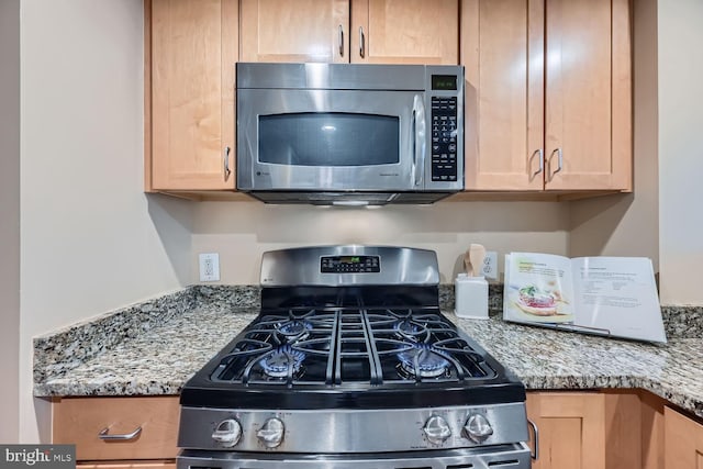 kitchen with appliances with stainless steel finishes, light stone countertops, and light brown cabinetry