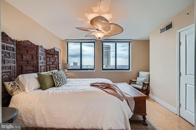 bedroom with baseboards, a ceiling fan, visible vents, and light wood-style floors