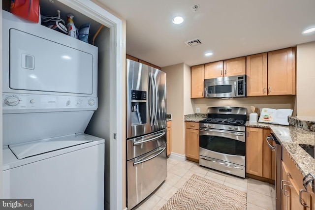 kitchen featuring visible vents, stacked washer / dryer, light stone countertops, stainless steel appliances, and recessed lighting