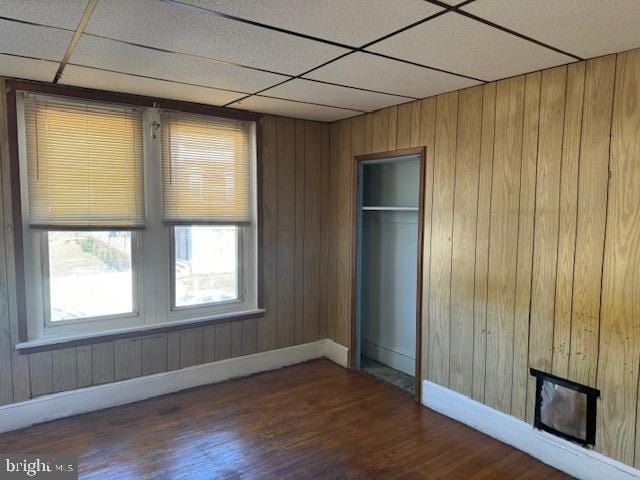 interior space with a closet, a paneled ceiling, dark wood-style flooring, and baseboards