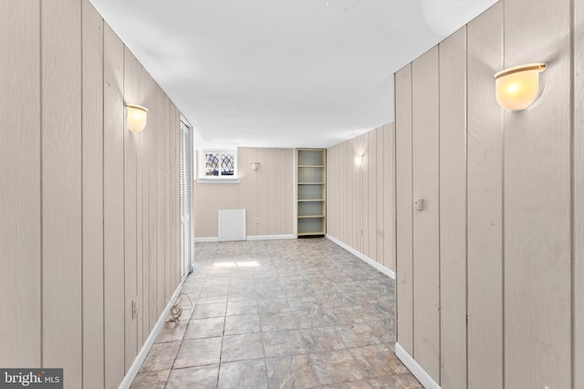 hall featuring wood walls, visible vents, and baseboards